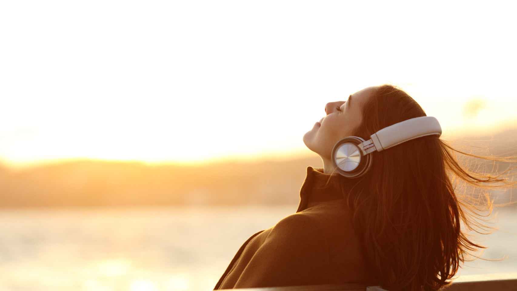 Mujer escuchando música en un banco. Foto: iStock.