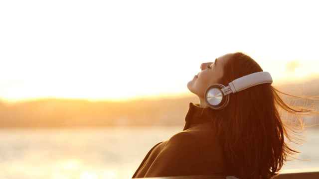 Mujer escuchando música en un banco. Foto: iStock.