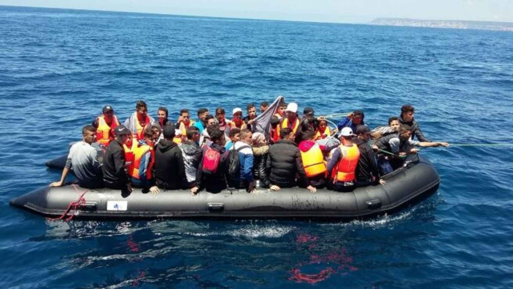 Inmigrantes a bordo de una lancha neumática, cerca de la costa.