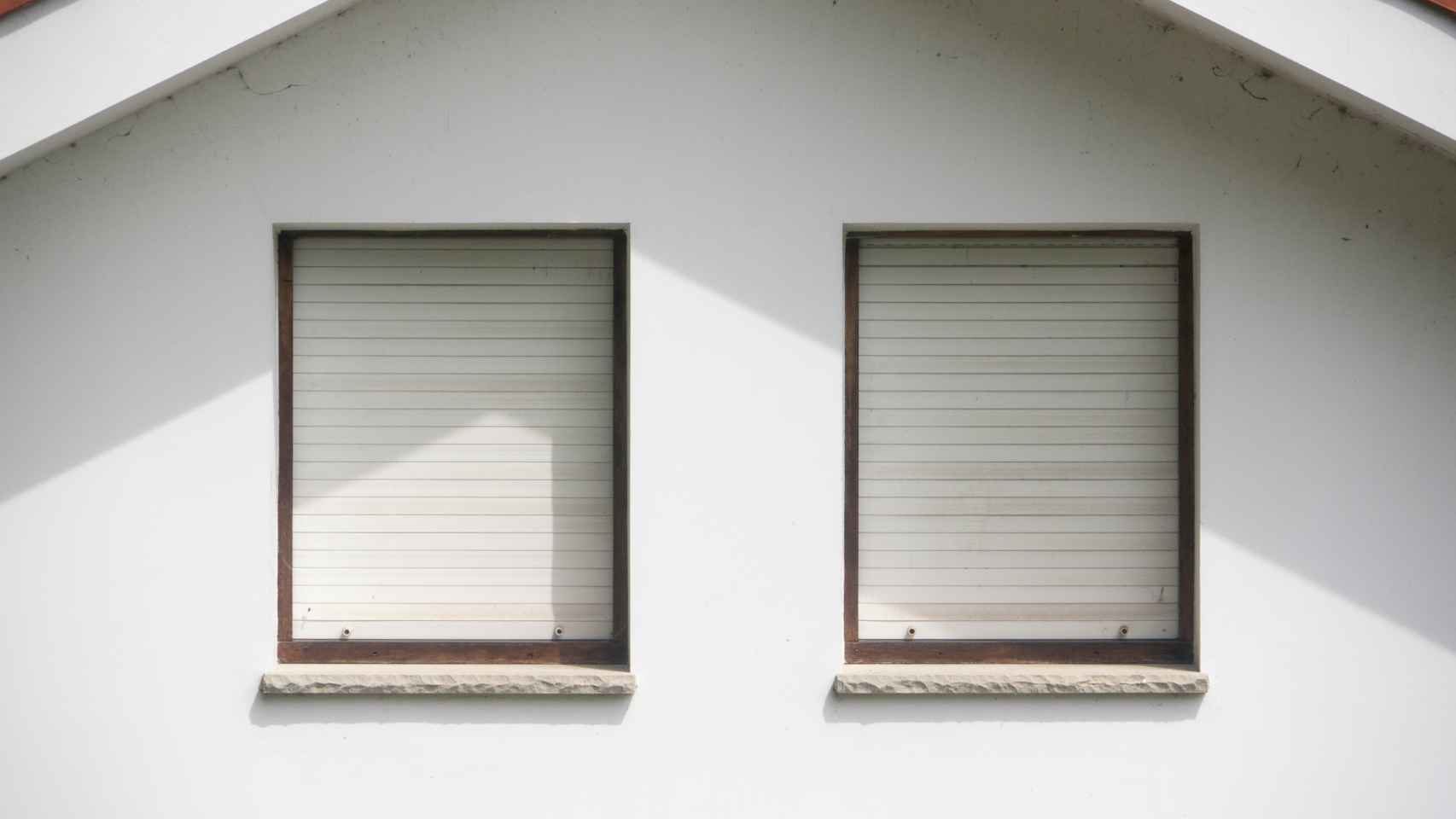Dos ventanas con persianas bajadas de color blanco. Foto: iStock.