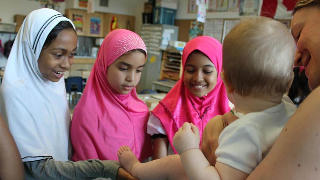 Un grupo de niñas interactúa con uno de los bebés del programa.