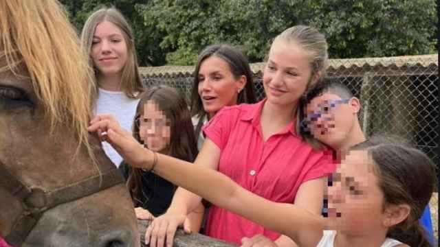 La reina Letizia y sus hijas, Leonor y Sofía, acariciando a un caballo mientras charlan con tres menores, este viernes 4 de agosto.