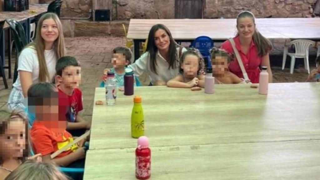 La Reina junto a sus hijas, muy sonrientes posando ante la cámara junto a algunos niños que conforman la granja escuela.