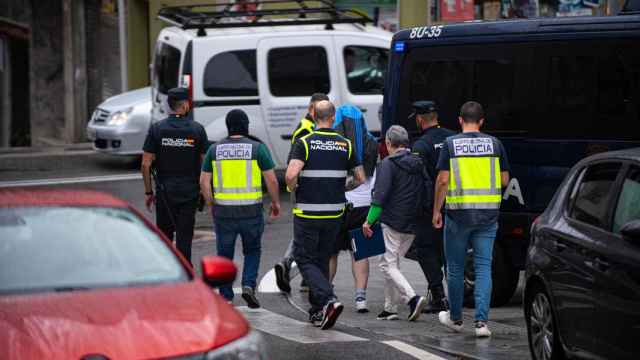 Agentes de policía trasladan a un detenido durante un operativo policial en Sanxenxo.