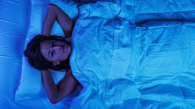 Imagen de archivo de una mujer joven en la cama con insomnio.