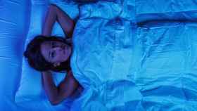 Imagen de archivo de una mujer joven en la cama con insomnio.