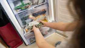 Imagen de archivo de una mujer sacando alimentos del frigorífico.