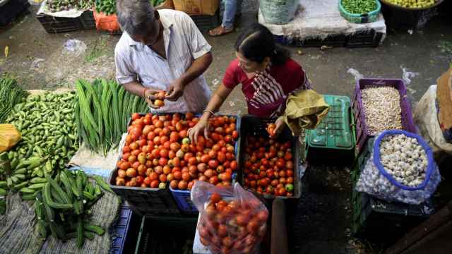Una mujer selecciona tomates de un vendedor en un mercado mayorista de Navi (Bombay).
