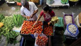Una mujer selecciona tomates de un vendedor en un mercado mayorista de Navi (Bombay).