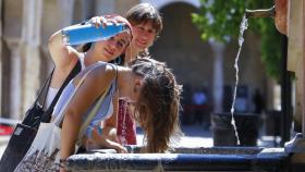 Unos niños se refrescan en una fuente de agua.