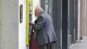 Un anciano sacando dinero de un cajero automático.