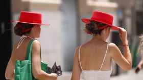Dos jóvenes caminan por el centro de Málaga con sombreros para protegerse del sol.