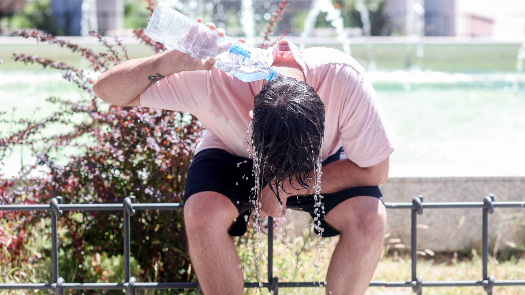 Una joven se refresca la cabeza con agua en Madrid.