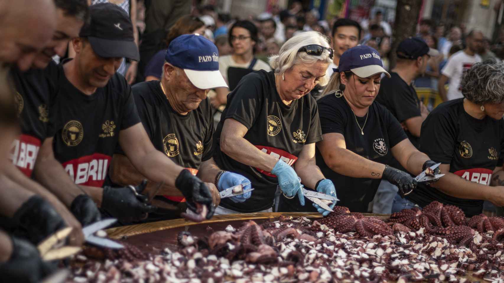 Pulpeiras y pulpeiros concentrados en la preparación de la tapa de pulpo más grande del mundo