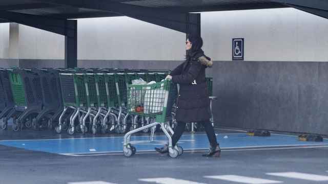 Una mujer sale de un supermercado con un carro.
