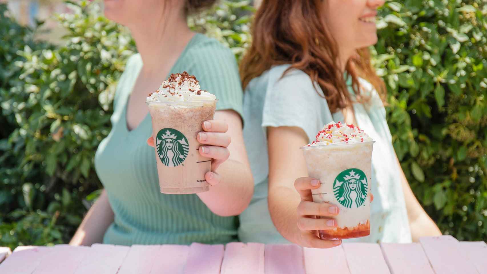 Dos chicas sostienen sus bebidas de Starbucks.