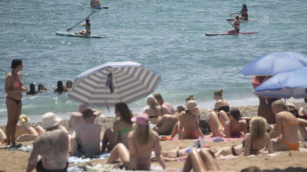 Veraneantes tomando el sol y disfrutando de un baño en la playa