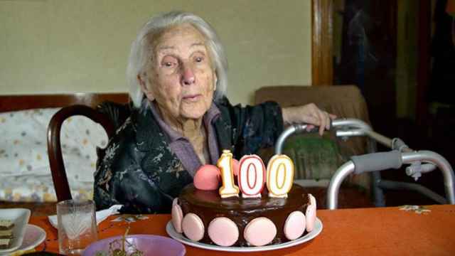 Una mujer sopla las velas de su cumpleaños número 100.