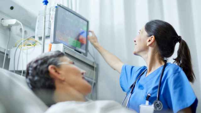 Imagen de archivo de una enfermera mirando a una pantalla y una paciente a su lado.