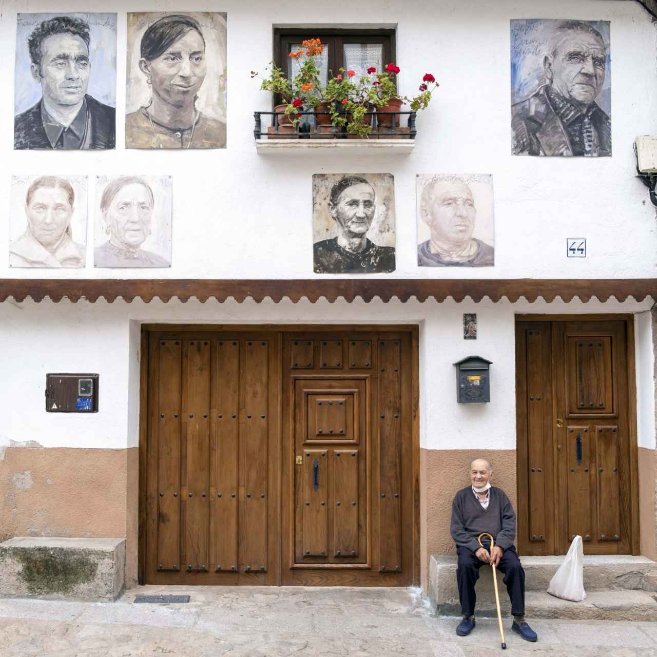 X Aniversario de la exposición ''Retrata2-388'' del artista Florencio Maillo, en el pueblo de Mogarraz. En la imagen un vecino del pueblo en la puerta de su casa donde entre otros está colocado su retrato.
