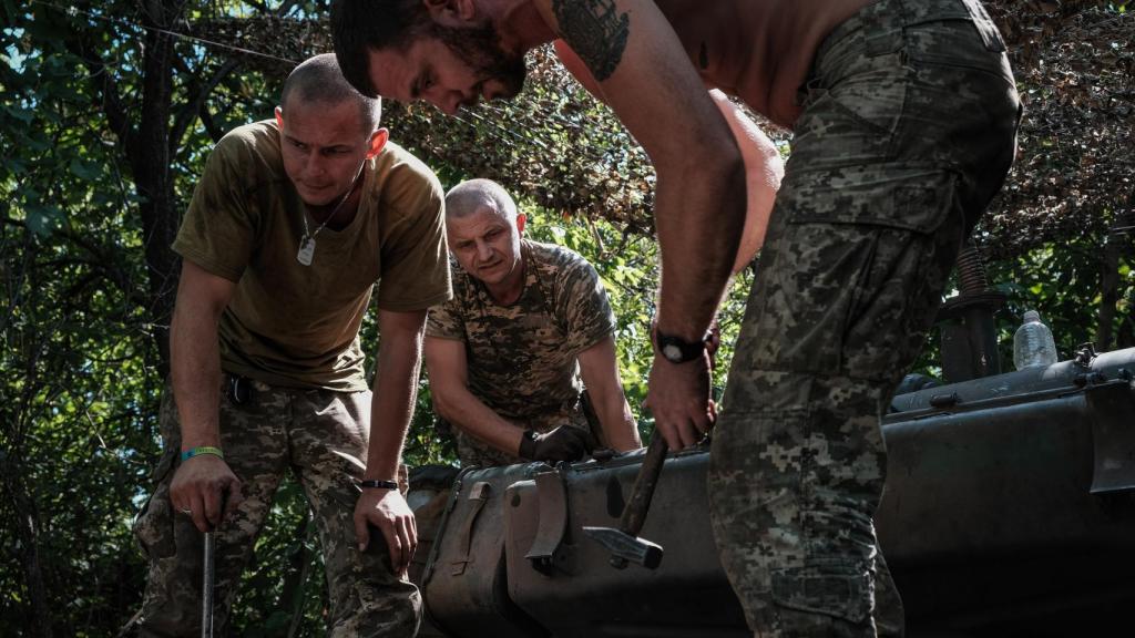 Los tripulantes de un carro de combate T-64 reparan el vehículo tras una misión, en pleno frente de Donetsk