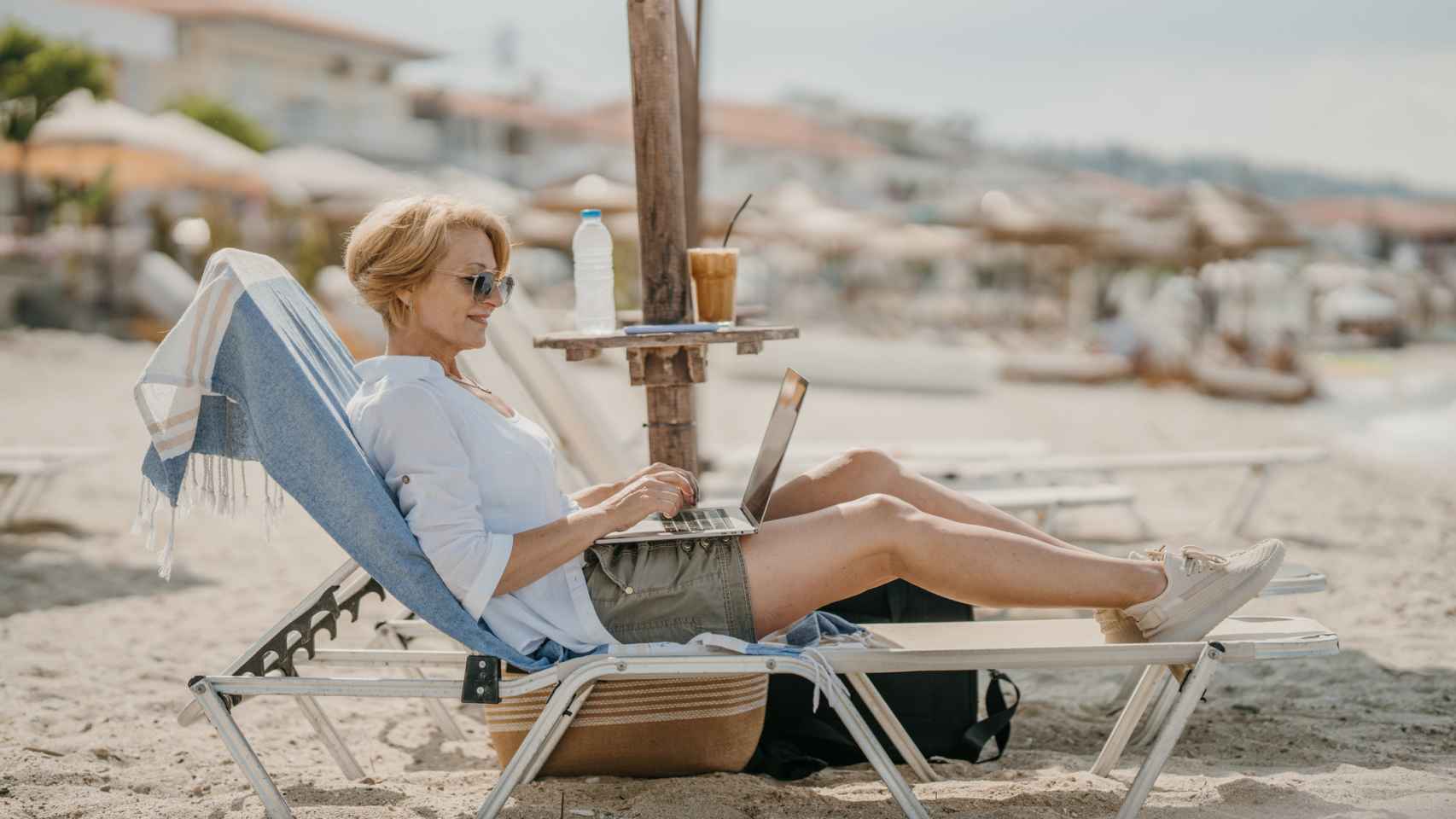 Una mujer conectada a su empresa en la playa.