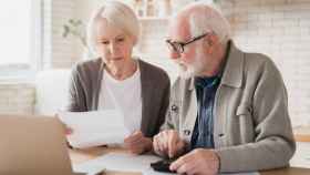 Dos jubilados revisan los papeles de la pensión.