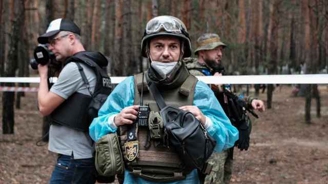 Un periodista junto a soldados y técnicos forenses en la apertura de la fosa común de Izyum (Járkov).
