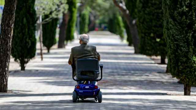 Un anciano en silla de ruedas eléctrica en un parque.