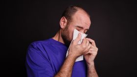 Un joven se limpia la nariz tras un estornudo.