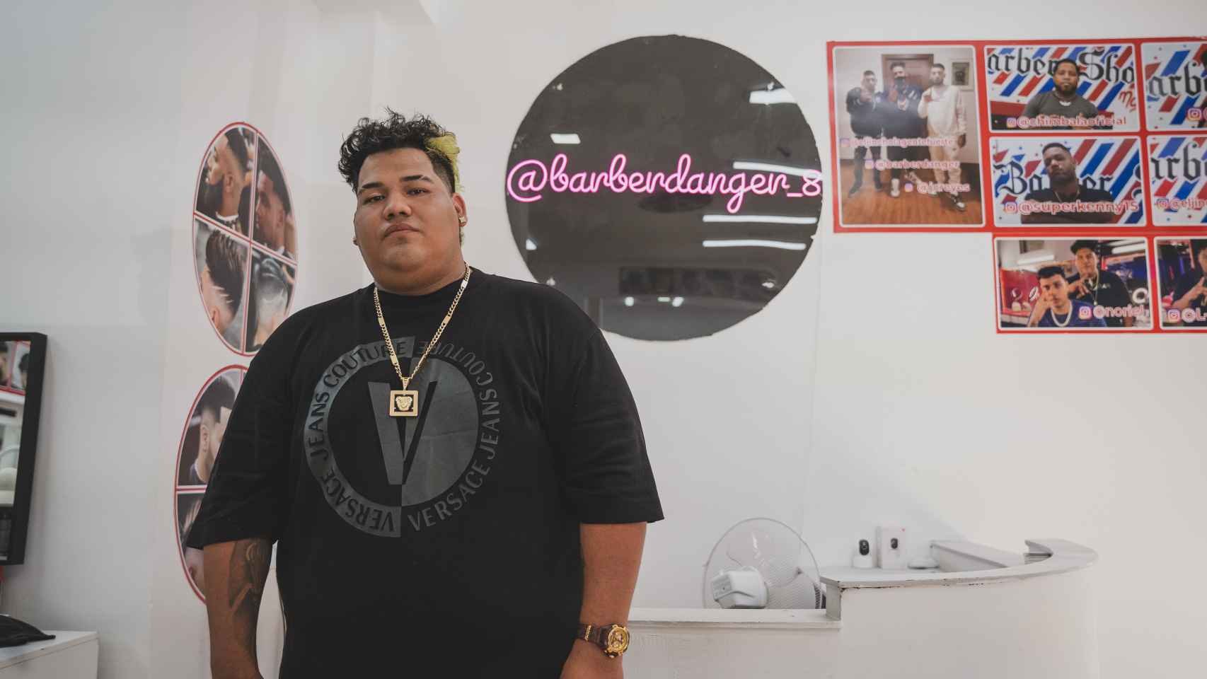 Anthony Márquez en el mostrador y junto al cartel con su Instagram '@barberdanger_8'.