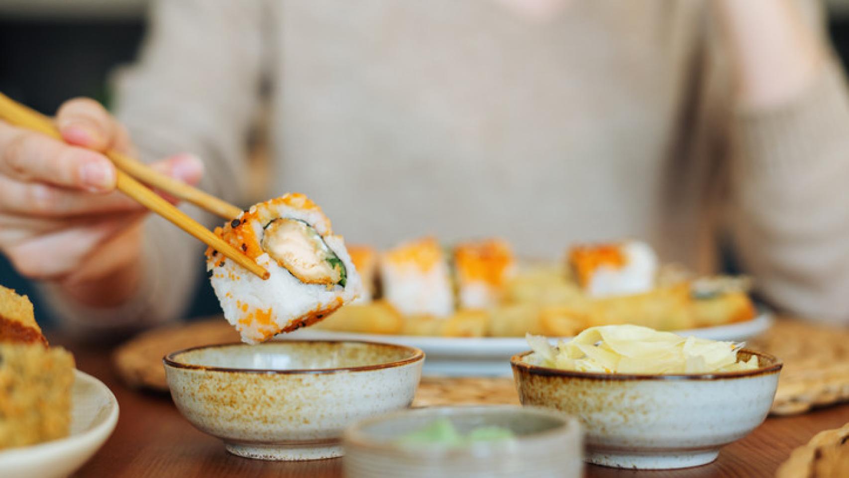 Una mujer comiendo un plato de sushi.