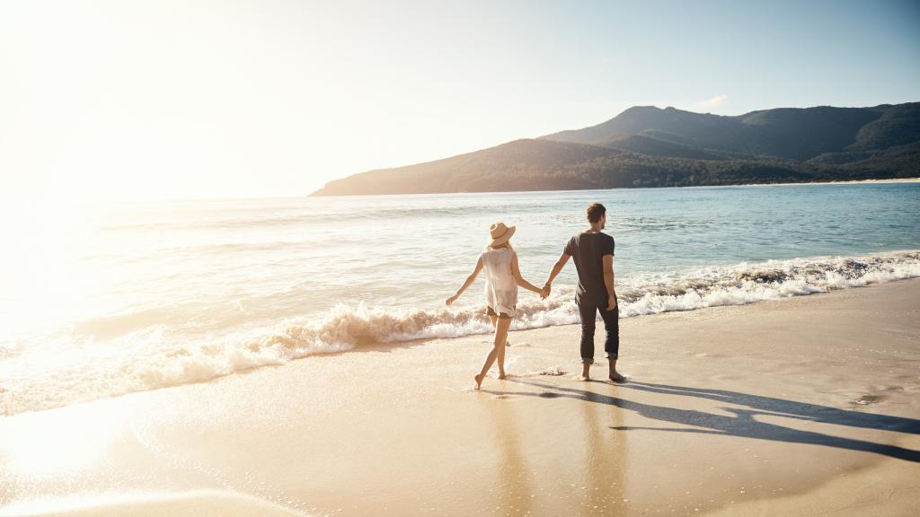 Una pareja pasea por la playa.