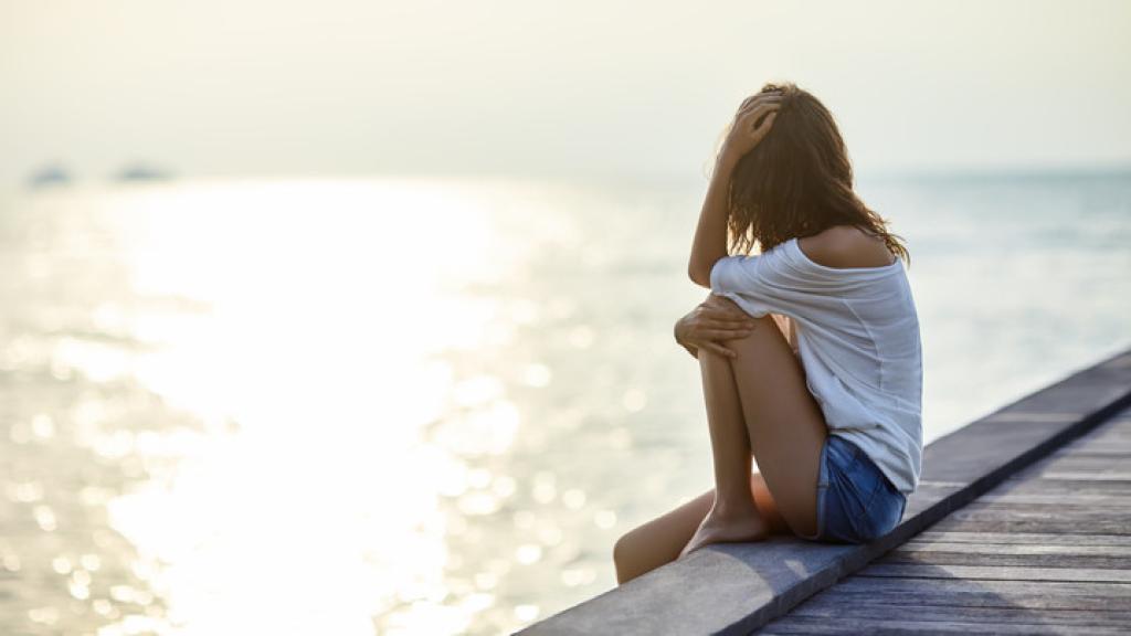 Una mujer sentada al lado del mar.