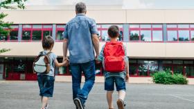 Un padre acompaña a su hijos al colegio.