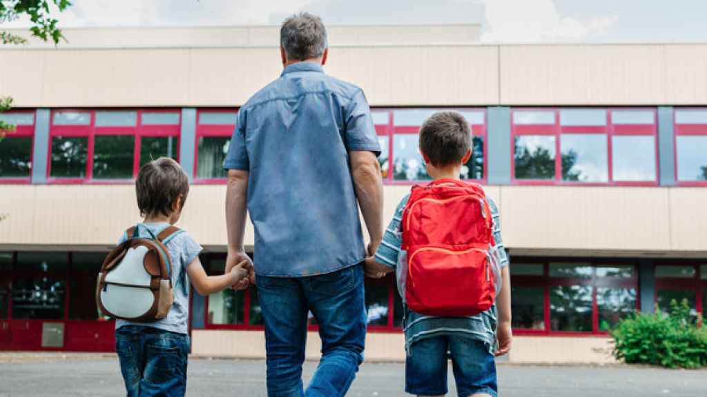 Un padre acompaña a su hijos al colegio.