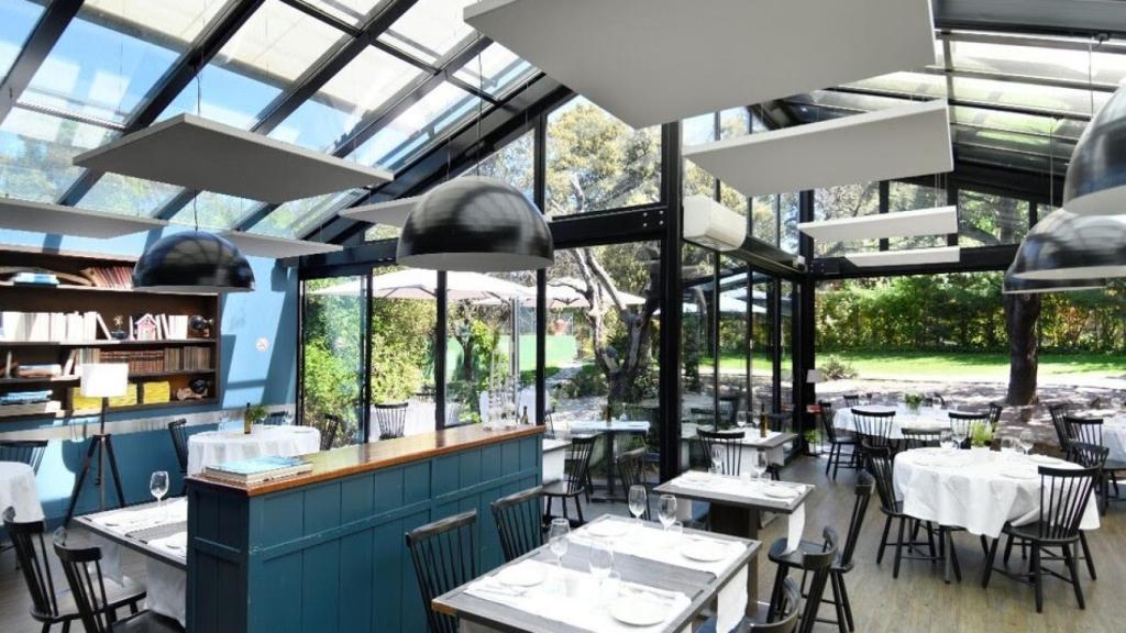 El interior del restaurante acristalado 'Cabaña Marconi' con vistas al jardín.