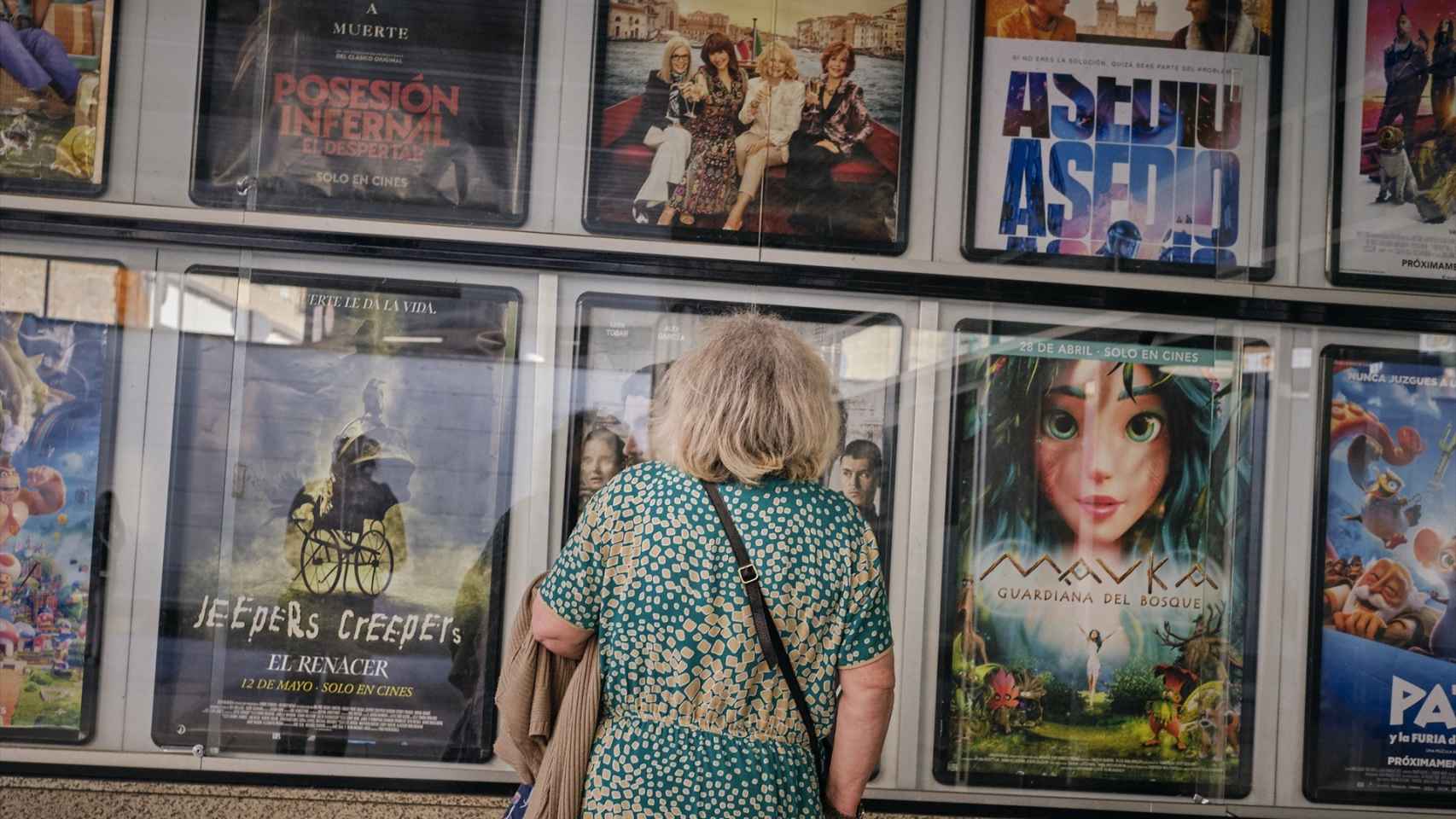 Una señora mayor frente a la cartelera de los Cines Galicine, en Orense.
