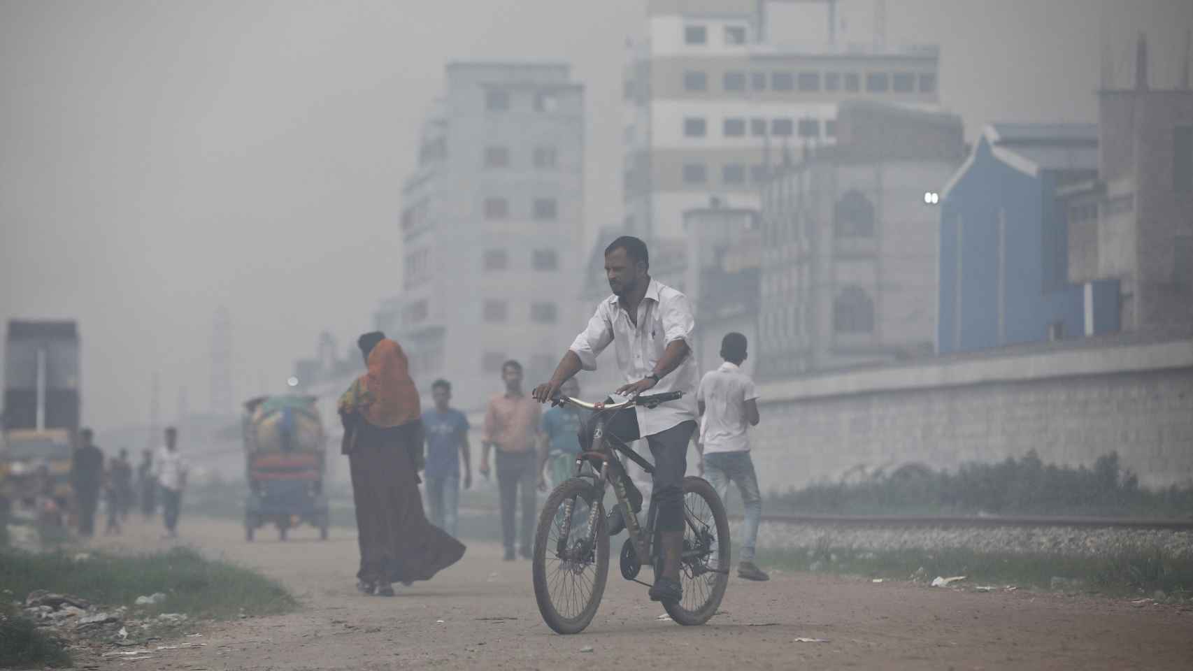 Imagen de archivo de un hombre que monta en bicicleta entre el humo que sale de las acerías situadas cerca de un barrio marginal de Dhaka.
