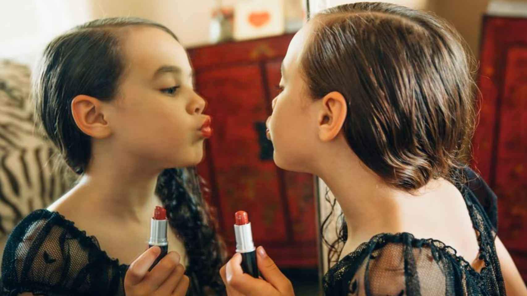 Una niña maquillándose como una mujer adulta.