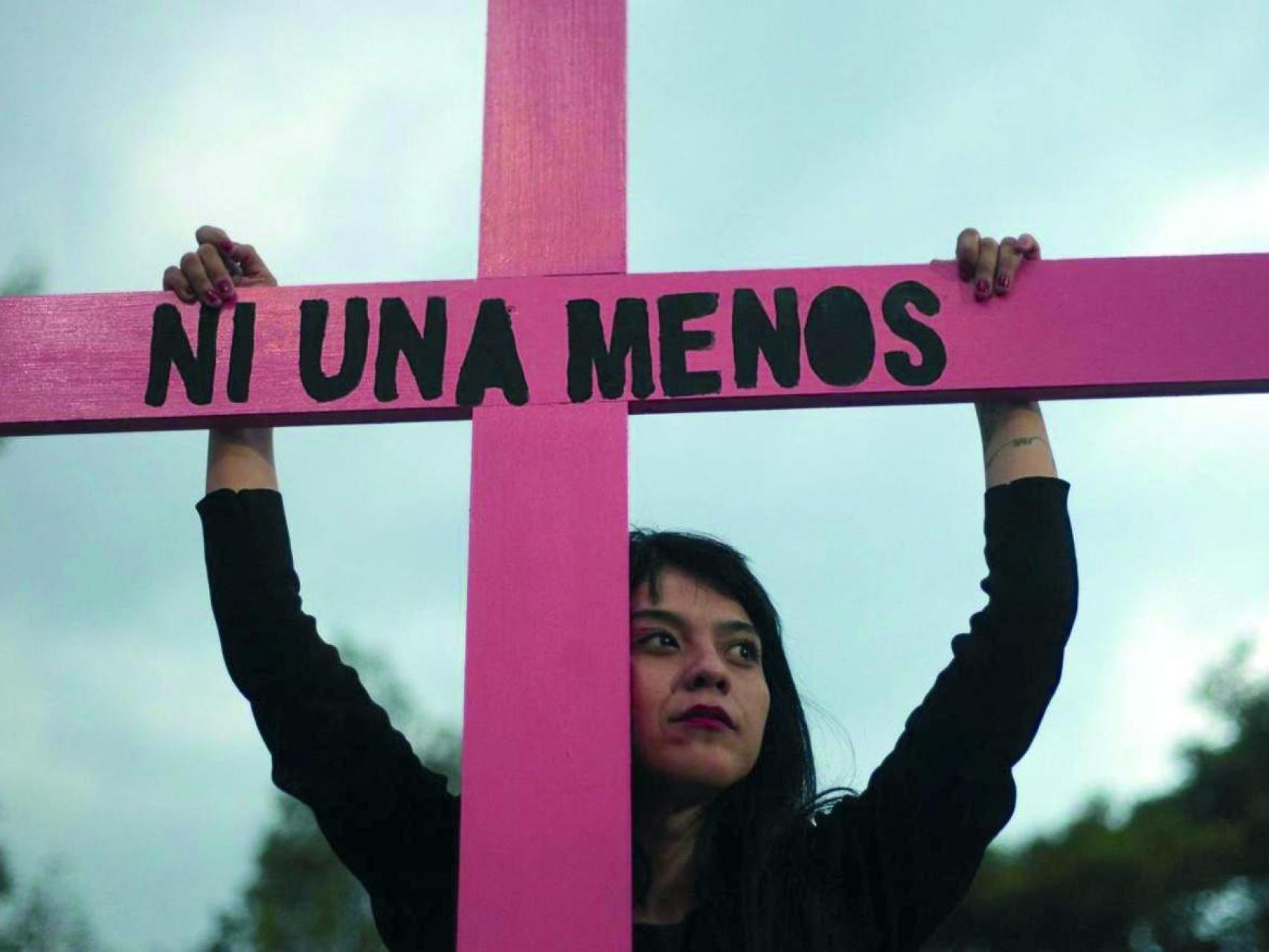 Una mujer porta una cruz de protesta contra la violencia machista.
