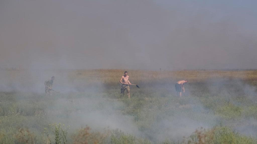 Soldados ucranianos apagan hierba quemada cerca de sus posiciones en la región de Zaporiyia.