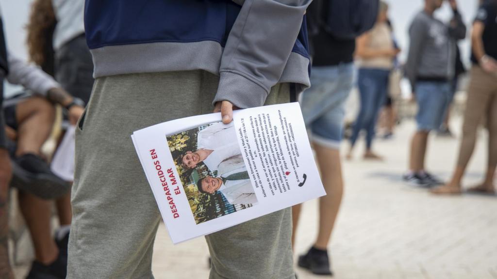 Un chico sostiene un cartel con la imagen de los jóvenes desaparecidos.
