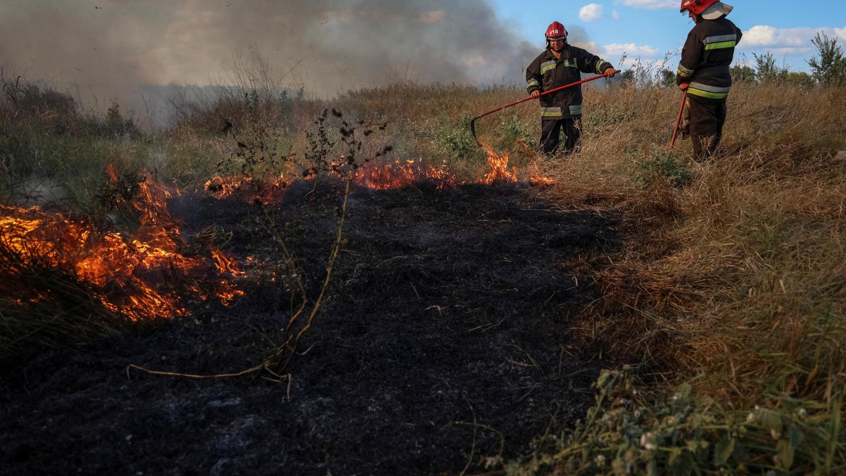 Los bomberos ucranianos apagan la hierba quemada cerca de sus posiciones en la región de Zaporiya.