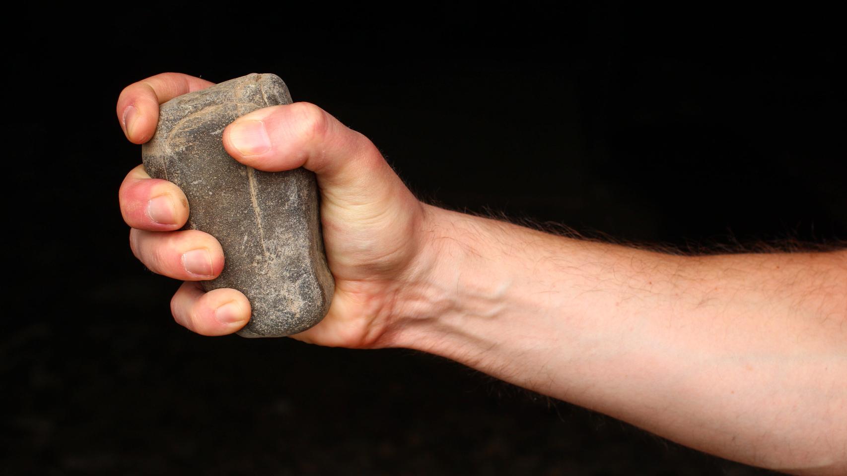 Imagen de archivo de una persona con una piedra en la mano.