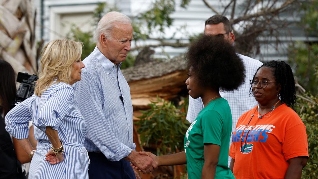 El presidente de Estados Unidos, Joe Biden, estrecha la mano de una mujer mientras recorren los destrozos causados por la tormenta del huracán Idalia en un barrio, 2 de septiembre de 2023.
