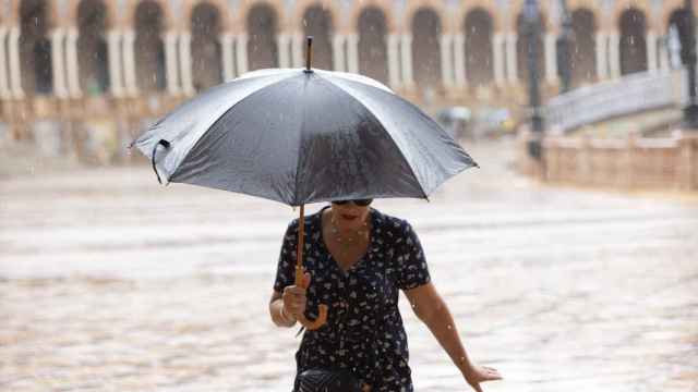 Una mujer se resguarda de la lluvia bajo su paraguas  en Sevilla.
