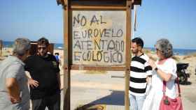 El eurodiputado de Anticapitalistas Miguel Urbán posa junto a una pintada contraria a la construcción del EuroVelo en las dunas de Cádiz.