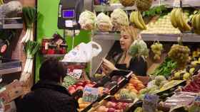 Un dependienta pesa una bolsa con frutas en las compras en los Mercados de Abastos en Sevilla.