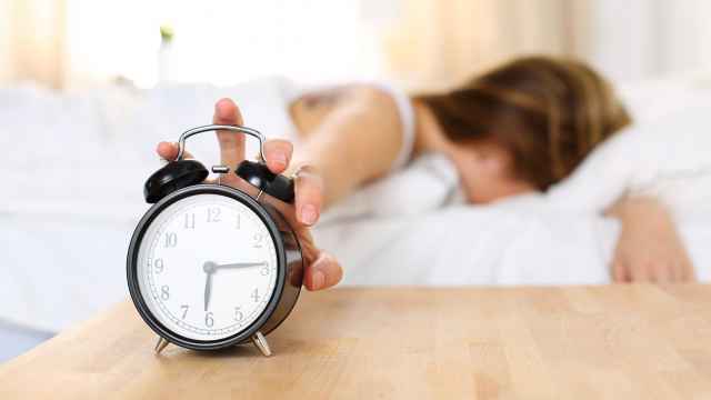 Una mujer apaga el despertador mientras suena para madrugar.